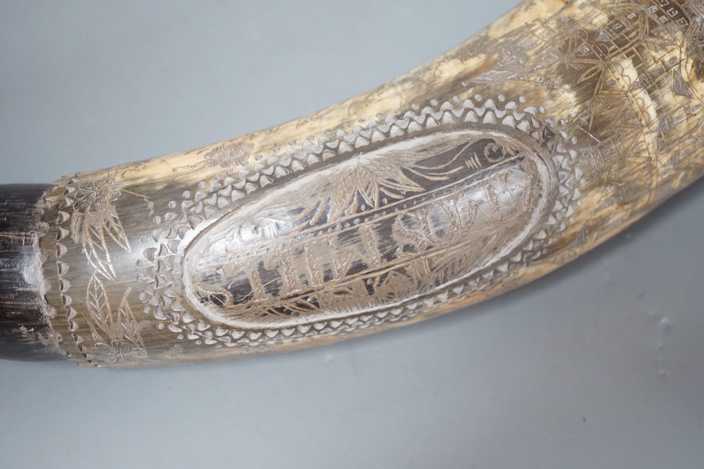 An early 19th century scrimshaw powder horn, ornately engraved with the Royal Coat of Arms, a castle and galleon and an inscription: Amos Mills. 38cms long.